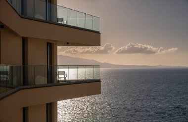 Saranda sahilinde denize bakan bir balkon manzarası. Gün batımında Deniz ve Dağların Balkon Manzarası. Denizde tatil. Güzel deniz manzaralı bir villa. Güzel modern apartmanlar lüks balkonlar.