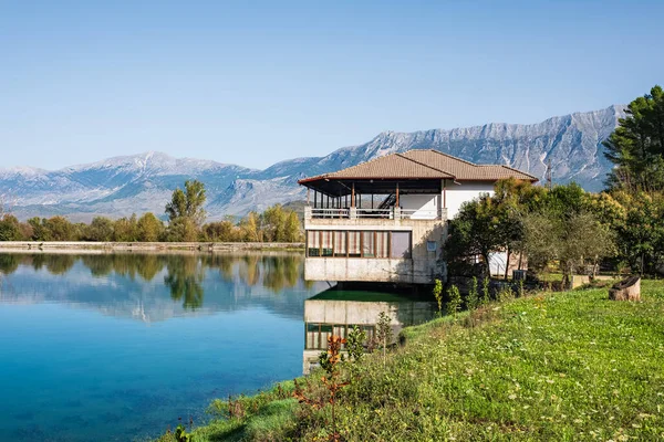 House on the shore of a lake in Albania. Mountain lake house on a sunny summer day. Cottage at the lake. Travel photo, nobody, copyspace for text