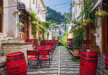 Açık hava boş kahve ve renkli masaları ve sandalyeleri olan restoran terası. Berat Arnavutluk 'taki eski moda kafe terası. Restoran verandası mobilyası. 9 Kasım 2023