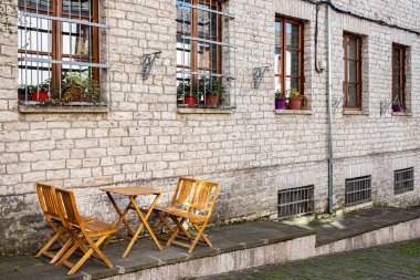 Eski kasabadaki açık hava kafeteryasında. Kafedeki boş terasta sandalyeler ve masa. Geleneksel açık hava kafesi, ahşap sandalye ve kaldırım taşı sokağındaki masa. Cirokaster Arnavutluk 'ta eski ve rahat bir cadde. Seyahat fotoğrafı.