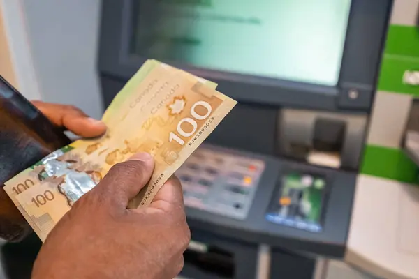 Cash withdrawal at an ATM. Money in the hands of close-up. Canadian dollars banknotes and cash machine. Money in hands. Man\'s hand withdrawing cash. Finance customer and banking service concept