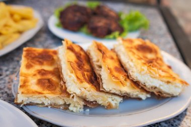 Peynirli Burek, ulusal yemek, Balkanlar 'da popüler. Byrek geleneksel Arnavut yemekleri peynirle yapılır. Feta ve Flaky Filo Pastası ile Byrek Peynirli Turta Kahvaltı Servisi