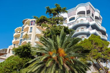 Palmiye ağaçları olan yeni modern mimari. Gayrimenkule yatırım. Arnavutluk 'ta bir yerleşim yeri. Kira, kredi kartı, bir daire satın alma. Balkonlu güzel, modern apartmanlar.