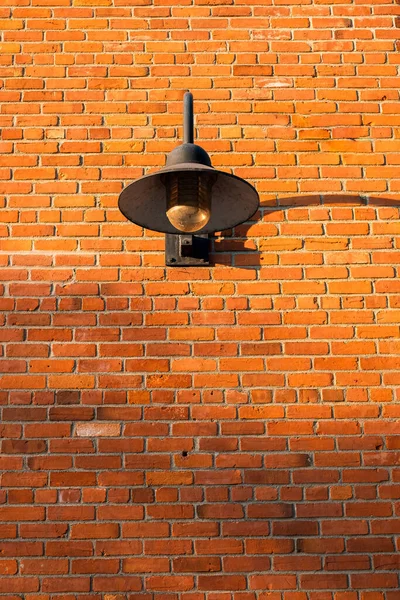 Vintage old street lantern with on a brick wall. Wall street light. Old style lantern, brick wall with shadow. Old grunge street. Grungy urban background of a brick wall