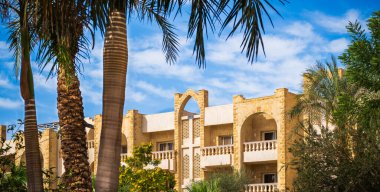 Villas, açık güneşli bir günde, mavi gökyüzünde beyaz bulutlarla birlikte gelişimini tamamlıyor. Arap tarzı daireleri ve balkonları olan bir ev. Hiç kimse, sokak fotoğrafı.