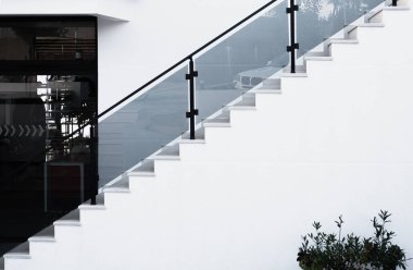 White steps with glass railing. Stone staircase in residential house, building of construction industry. Concrete steps. View of concrete steps and railing leading to an entrance in a modern building clipart