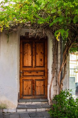 Eski taş duvardaki eski ahşap kapı. Basit, eski moda bir köy evinin sokak manzarası. Eski kırsal ahşap kapı geleneksel mimari elementler