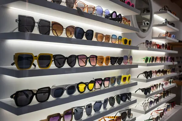 Storefront shelves of various modern sunglasses in retail store. Display rack full of sunglasses. Stand with sunglasses. Fashionable Trendy sunglasses, Summer eyeglasses on the shop shelf