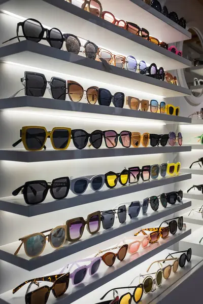 Storefront shelves of various modern sunglasses in retail store. Display rack full of sunglasses. Stand with sunglasses. Fashionable Trendy sunglasses, Summer eyeglasses on the shop shelf