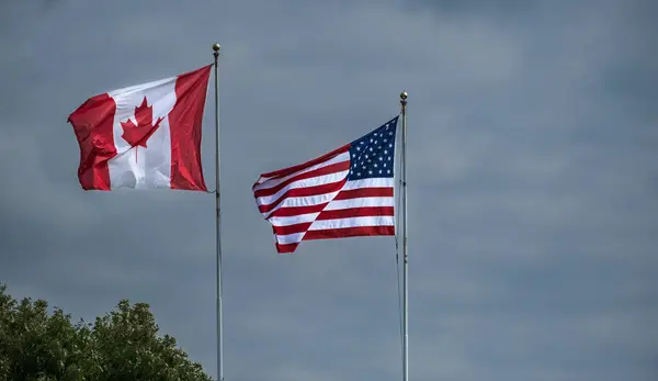American and Canadian flags together. American and Canadian flags flying side by side at the border between USA and Canada at Peace Arch Blaine. Travel photo, nobody, copy space for text