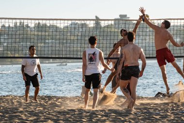 Plaj voleybolu oynayan arkadaşlar. Sahilde eğlenen çok ahlaklı bir grup insan. Sportif aktif yaşam tarzı. Sağlıklı bir hayat süren gençler plajda spor yapıyorlar. 14 Eylül 2023 - Vancouver Kanada