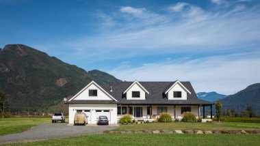 Çiftlik arazisinde inşa edilmiş büyük bir aile evi. Britanya Kolumbiyası 'nda güneşli bir günde önünde büyük yeşil çimenler olan bir ev. Tipik Kuzey Amerika Çiftlik Evi