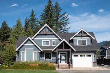 Güneşli bir günde gayrimenkul paravanı. Vancouver Kanada 'nın banliyölerinde bahçe ve garaj yolu güzel döşenmiş lüks bir ev.