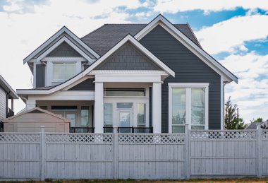 Güneşli bir günde gayrimenkul paravanı. Yazın bahçeli ve çitli lüks bir ev. Yeşil çimenli güzel bir ev girişi. Mükemmel bir mahalle.