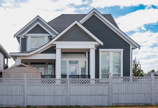 Güneşli bir günde gayrimenkul paravanı. Yazın bahçeli ve çitli lüks bir ev. Yeşil çimenli güzel bir ev girişi. Mükemmel bir mahalle.