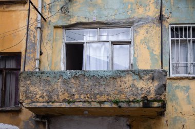 Balkonlu eski bir bina. Yaşayan basit insanlar. Yıpranmış konut bloğu. Hasarlı duvarları ve balkonları olan eski gecekondu evinin ön cephesi. Tehlike panelinde pencereler ve balkon