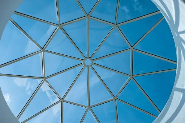Glass ceiling in blue sky sunlight, abstract. Glass roof of the building. Geometrical ceiling, limpid round ceiling. Glass roof of the building over blue sky, transparent roof, skylight roof