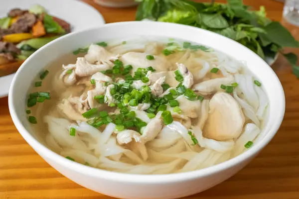 Pho noodle, traditional Vietnamese food, rice noodle soup with sherd chicken with cilantro, mint and Thai basil, Vietnamese cuisine soup Pho Ga with chicken, rice noodles and fresh herbs in a bowl