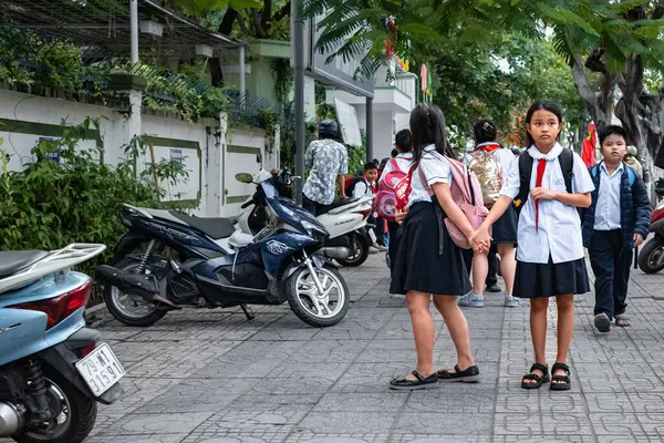 在课间休息的时候 当地的小学生在学校里 街上的年轻越南女学生 穿着越南校服 打着红色领带的孩子 街头照片 Nha Trang March 2024 图库照片