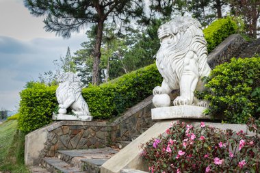 Aslan heykelleri. Da Lat Vietnam 'daki halk parkının önündeki merdivenlerde iki mermer aslan oturuyor. Seyahat fotoğrafı, kimse yok.