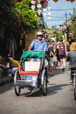 Vietnam Taksisi üç tekerlekli servis turistleri şehirde bisikletle dolaşıyorlar. Vietnamlı işçiler servis yolcuları için üç tekerlekli çekçekli bisiklet kullanıyor. Cyclo en sevilen araçtır-Hoi An Vietnam-22 Mayıs 2024