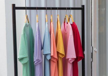 Dükkanda sergilenen çok renkli tişörtler. Giysiler beyaz arkaplanda. Butikte satılık tişörtler. Giysi dükkanı. Kıyafet dükkanı..