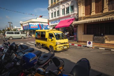 Tayland. Phuket Yellow Tuk Tuk yerel taksi servisi Çin-Portekiz binaları ile birlikte. Caddenin kenarına park etmiş motosikletler. Eski kasabadaki dükkanlar ve restoranlar. 26 Haziran 2024