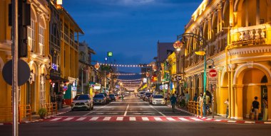 Phuket, Tayland. Phuket Eski Kasabası 'ndaki eski Çin-Portekiz binalarının olduğu ve akşamları sokakta dolaşan turistlerin olduğu eski bir kasabanın gece manzarası. Işıklı dükkanlar ve restoranlar. 26 Haziran 2024
