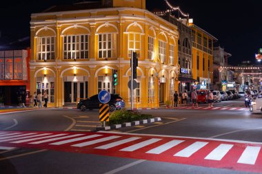 Phuket, Tayland. Phuket Eski Kasabası 'ndaki eski Çin-Portekiz binalarının olduğu ve akşamları sokakta dolaşan turistlerin olduğu eski bir kasabanın gece manzarası. Işıklı dükkanlar ve restoranlar. 26 Haziran 2024