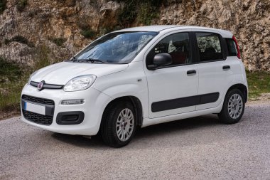 Yolun kenarına park edilmiş küçük bir araba. Beyaz hatchback arabaları yolda. Bütçeli araba kiralama ve perakende konsepti. 4 koltuklu güvenilir ekonomik otomobil. Kimse.
