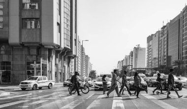 Şehirdeki iş yerlerinde iş çıkış saatlerinde zebra üzerinde yürüyen insanlar Abu Dabi BAE 'den geçiyorlar. Karşıdan karşıya geçen insanlar. Şehir sokakları zebrayla dolu. 27 Ocak 2024.