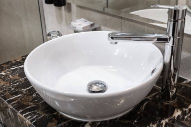 Yeni lüks bir evin ana banyosunda lavabo ve gösteriş. Modern stil banyo süsü, mermer kaplamalı bir tezgah. Modern banyoda lavabosu olan musluk.