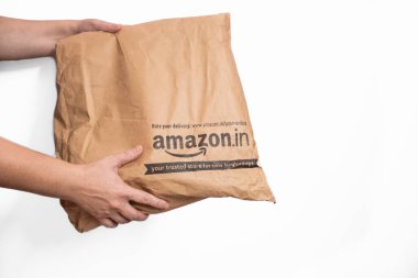 Amazon Hindistan 'dan eve teslim edilmiş kağıt paketi. Amazon.Etiket paketleme çantası beyaz arka planda izole edilmiş. Kadın eller online dağıtım için bir Amazon kutusu alıyorlar - Goa, Hindistan-Eylül 14. 2024