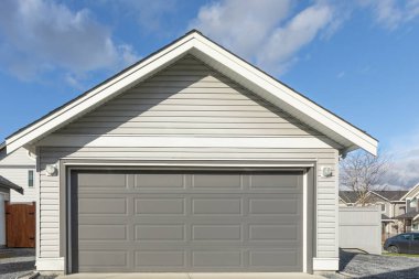 Garaj kapısı. Kapalı beyaz garaj kapısı olan modern bir ev. Mükemmel bir mahalle. Geniş garaj kapısı ve önünde beton yol olan bir aile evi. Sokak fotoğrafı, kimse yok.