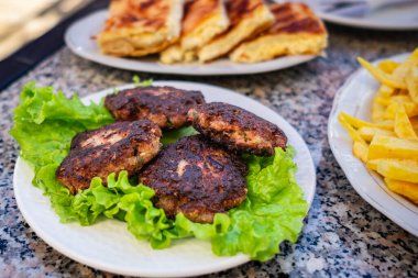 Kızarmış burger pirzolası ve salata yaprakları yuvarlak şekilli köfte ve patates kızartması. Tabakta marullu kızarmış pirzola burger. Tabakta ev yapımı Kofte