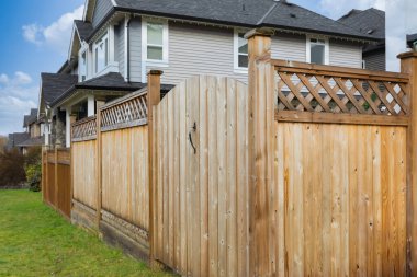 Evin ve ağaçların etrafında büyük yeni ahşap çitler var. Yeşil ağaçlı ve patikalı sert ahşap çitler. Eskrim ve kapılar. Yüksek kalite çalıntı mal. Sokak fotoğrafı. Eskrim ve kapılar. Kanada Kerestesi, Kırmızı Sedir.