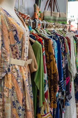 Mağazada çeşitli elbiseler var. Renkli giyim mağazası. Mağazada asılı renkli yaz elbiseleri. Kürsüde asılı kadın kıyafetleri. Kimse.