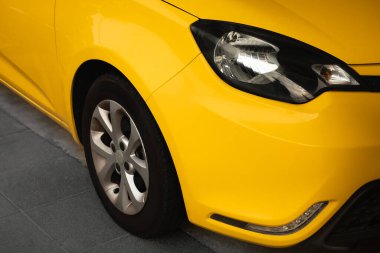 Araba farları ve tekerlek gösterisi. Dışarıya park edilmiş sarı, yeni, modern lüks arabanın ön manzarası. Farlar ve sarı arabanın tekerlek ayrıntıları. Zarif tasarım araba ışıkları. Araç endüstrisi