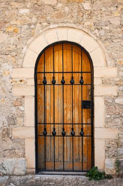 Duvarında dövülmüş metal ızgara olan kapı. Sahte kafesli ahşap kapı. Köy taşından bir duvarda kafesi olan eski ahşap bir kapı. Mimari binalar, eski kapılar, kemerler, kafes kapıları.