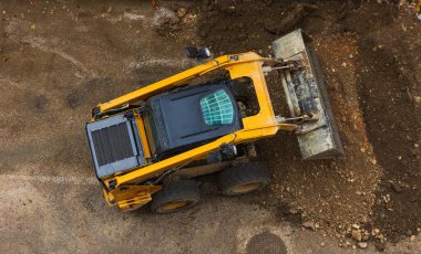 Güçlü buldozer ya da yükleyici inşaat alanında toprağı yerinden oynatır. Toprak hareket eden bir makine alanı düzleştiriyor. Toprak işçiliği için ağır ekipmanlar inşa ediliyor. Yukarıdan görüntüle.
