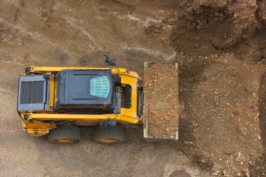 Güçlü buldozer ya da yükleyici inşaat alanında toprağı yerinden oynatır. Toprak hareket eden bir makine alanı düzleştiriyor. Toprak işçiliği için ağır ekipmanlar inşa ediliyor. Yukarıdan görüntüle.