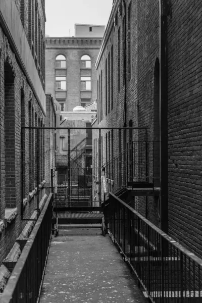 Şehirdeki iki tuğla ev arasındaki dar bir sokak. Korkuluklu ve merdivenli geçit. Metal merdivenli sokak. Sokak manzarası, seyahat fotoğrafı.