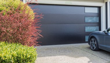 Pencereli gri garaj kapısı ve önünde park etmiş bir araba. Vancouver, Kanada. Lüks evdeki garaj kapısı. Sokak fotoğrafı, hiç kimse, garaj kapısı. Yalıtılmış garaj kapısı.