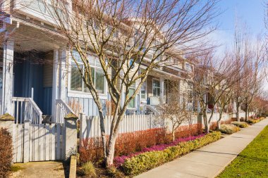 İki katlı evler. Sokaktaki evlere bağlanmış. Kuzey Amerika 'daki kasaba evleri. Evlerin önünde ağaçlar ve yürüyüş yolu olan güzel evler..