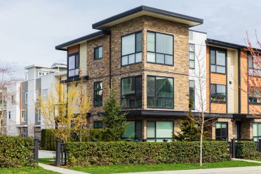 Kuzey Amerika 'da yeni inşa edilmiş bir apartman. Apartman dairesi. İkametgah dairesi. Lüks daireler. Gayrimenkul. Arkasında ağaçlar ve gökyüzü olan apartman evleri.