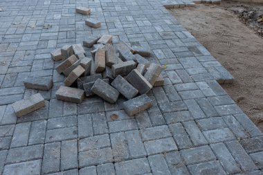 İnşaat alanı. Yaya üzerine tuğla döşeniyor. Asfalt döşeme ve sınırlar. Yol çalışması, gri beton döşeme döşemesi. Şehrin yaya bölgesine kaldırım tuğlaları yerleştirme süreci