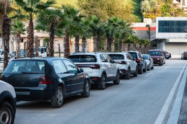 Arabalar Avrupa 'nın banliyösünde ağaçlık bir yerleşim caddesi boyunca park halindeydi. Şehir caddesi boyunca park edilmiş sıra sıra arabalar. Şehir ulaşımı, park yönetimi çözümleri. Park etmiş arabalarla dolu bir cadde.
