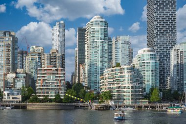 Vancouver şehir merkezi. Yatlar ve yelkenliler güneşli bir günde Blue Sky 'ın altındaki False Creek' e demirlediler. BC Kanada 'da modern konut mimarisi. Seyahat fotoğrafı - 14 Ekim 2022