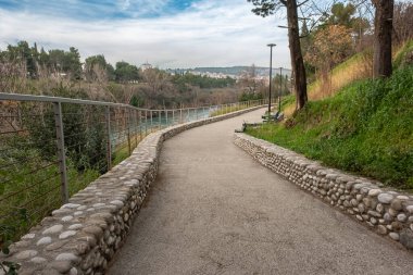 Şehir parkında kaldırım var. Yürüyüş için parkta güzel bir yürüyüş yolu. Parkta nehir manzaralı bir patika. Seyahat fotoğrafı, kimse yok.