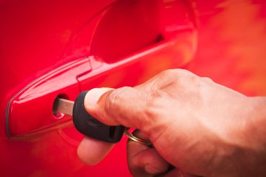 Adam, satın aldıktan sonra yepyeni bir arabanın kapısının dışından kırmızı bir arabanın kapısını açıyor. Seçici odaklanma. Boşluğu kopyala.